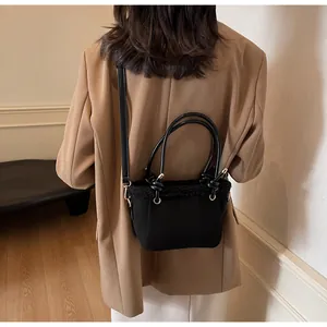Detail of a black matte crossbody bag with faux fur trim worn with a khaki blazer