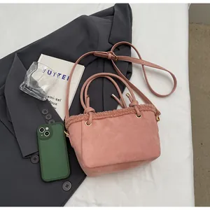 Flat lay of a pink suede crossbody bucket bag with faux shearling trim on bedding