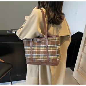 Detail of checkered tote bag in brown and green wool fabric on a khaki trench coat