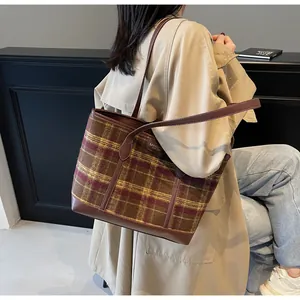 Detail of vintage plaid tote bag with brown leather straps and branded label patch
