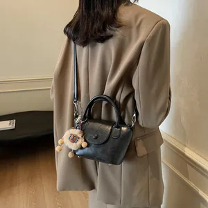 Retro black leather bucket bag with plush charm, shown on model with shoulder strap