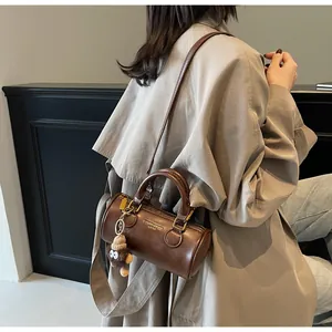 Close-up of vintage brown cylindrical crossbody bag with plush monkey charm on strap
