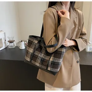 Close-up of vintage tartan tote bag with leather straps on a cafe counter