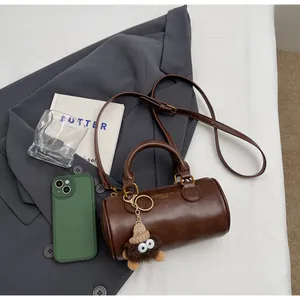 Detailed top view of a brown cylinder bag with PU leather texture and plush charm