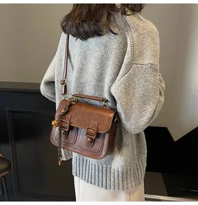 Close-up of vintage brown crossbody bag worn by model showing texture and woven charm