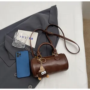 Detailed flat lay of brown retro barrel bag with plush charm and gold hardware accents