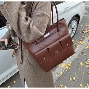 Détail d'un grand sac cabas en cuir marron foncé avec poches avant à fermoirs argentés