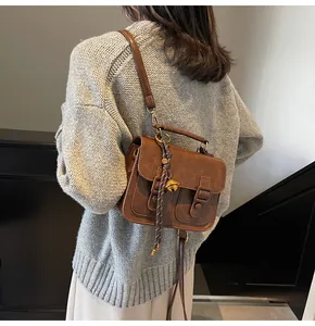 Detail of vintage brown satchel with dual front buckles and a bell charm decoration