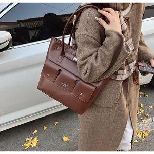 Détail d'un cabas en cuir caramel avec un fermoir rotatif sur la poche extérieure