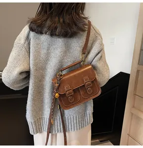 Retro brown leather satchel with dual buckle straps and side pendant detail