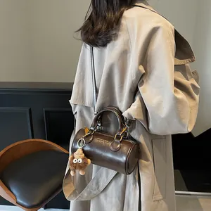 Vintage brown leather cylindrical cylinder handbag with lion plush charm and gold hardware