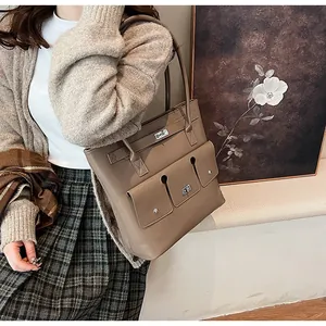 Détail d'un grand sac cabas kaki avec trois poches avant et fermoirs rotatifs argentés