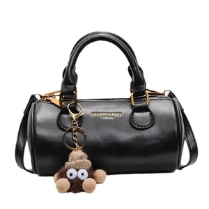 Classic black leather cylindrical Boston bag with gold lettering and plush charm accessory