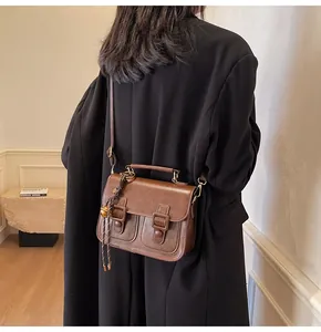 Close-up of a brown vintage leather messenger bag on a model wearing a black blazer