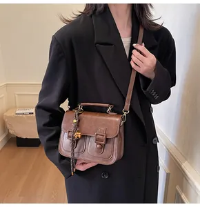 Detailed close-up of retro brown satchel with bell charm and adjustable shoulder strap