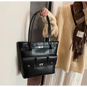 Détail du sac cabas en similicuir noir avec deux poches avant et fermoirs argentés rotatifs