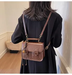 Detailed view of a brown vintage satchel bag with dual front pockets and metal ring handle