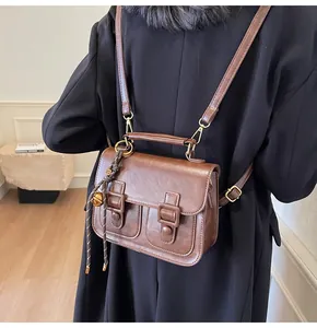 Detail of vintage dark brown faux leather backpack with metallic bell charm and straps