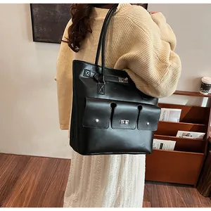 Détail du sac cabas en cuir noir avec fermoir rotatif argenté et poche avant à rabat