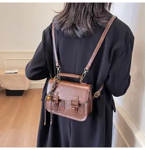 Rear view of vintage brown satchel with adjustable straps and top handle on a model