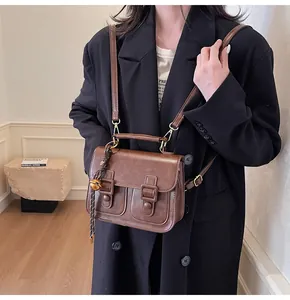 Detail of dark brown vintage satchel with gold hardware worn by a model in a black blazer