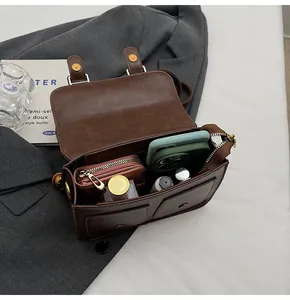 Internal storage capacity of brown vintage satchel bag showing daily essentials and phone