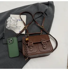 Flat lay of vintage brown leather satchel bag with stylish accessories and grey blazer