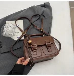 Close-up of a vintage brown leather backpack with buckle pockets on a grey blazer