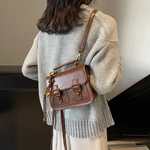 Retro brown satchel with double buckles and bell charm for women's autumn winter style
