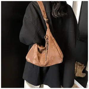 Detail of brown pleated handbag showing textured surface and decorative knotted pendant