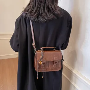 Vintage dark brown satchel bag with flap and metal buckles on a black oversized blazer