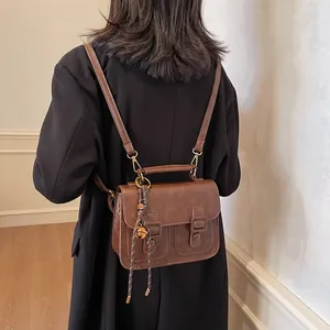 Vintage brown leather crossbody bag with dual buckles and bell charm shown on model
