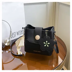 Detail of black leather bucket bag with silk scarf handle and golden fashion lettering