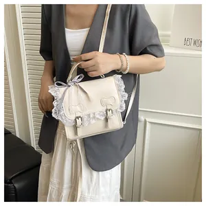 Detail of cream lace crossbody bag with leather bows and a gingham ribbon handle