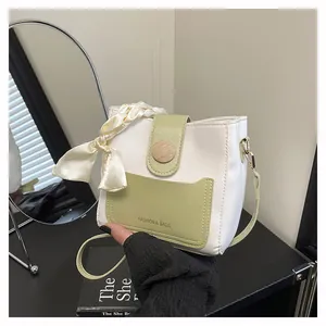 Detail of a chic bucket bag showing a green front pocket and a decorative silk scarf handle