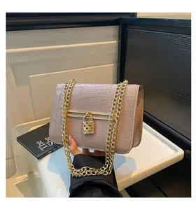 Detail of dusty pink crocodile pattern bag with gold heart padlock and chain strap