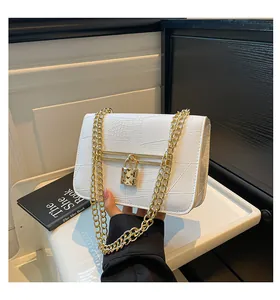Detail of white crocodile pattern shoulder bag with golden heart lock and chain strap