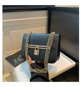 Detail of black crocodile texture bag with gold heart-shaped lock and double chain straps