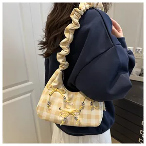 Detail der gelb karierten Crescent-Bag mit Kordelschleife und gerafftem Schultergurt