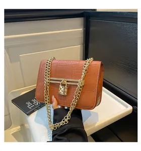 Close-up of the heart-shaped gold padlock and stone pattern on the brown leather bag