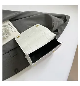 Close-up of white crocodile pattern texture and golden magnetic buckle on handbag