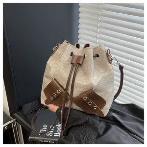 Detail view of canvas bucket bag with brown leather pockets and drawstring closure