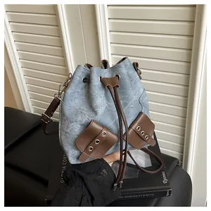 Macro detail of blue denim bucket bag with brown leather trim and metal eyelet pockets