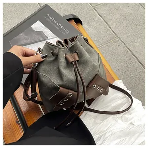 Detail of olive green canvas bucket bag with brown leather drawstring and side pocket
