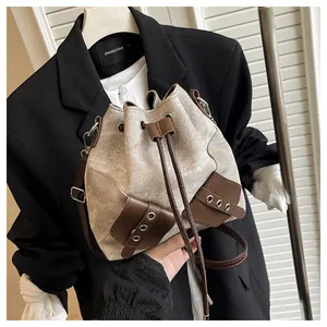 Detail of the drawstring bucket bag showing beige canvas texture and brown leather trim