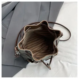 Top view detail of drawstring bucket bag with striped lining and faux leather trim