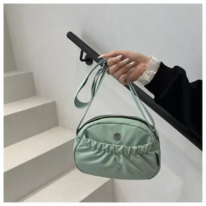 Close-up of mint green pleated shoulder bag featuring a silver metal M logo