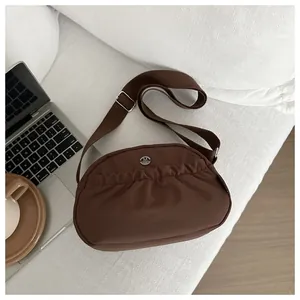 Detail of dark brown pleated nylon crossbody bag with metal M logo and wide strap
