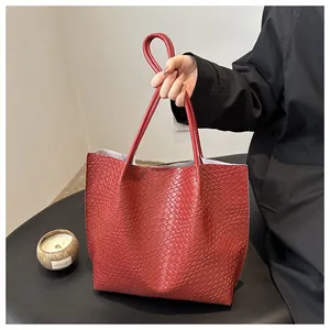 Close-up of red tote bag featuring intricate woven texture and leather carry handles