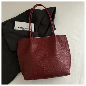 Detail of burgundy woven leather tote showing rich texture and slim dual shoulder straps